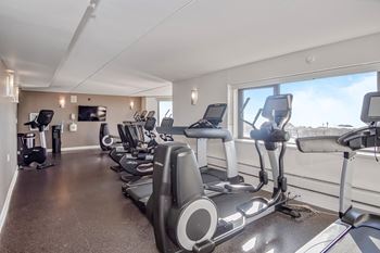 an exercise room with cardio equipment and a view of the cit at 10 West Apartments, New York